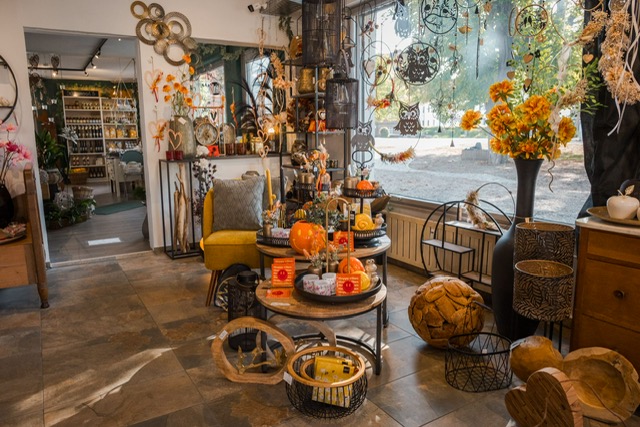 Herbstliche Dekoration mit orangefarbenen Kürbissen und Metallständern am Schaufenster